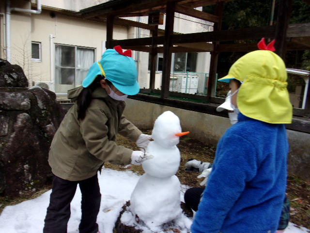 大小の雪玉を3段に積み上げている園児の写真