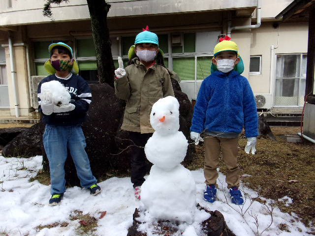 3段雪だるまの後ろに並んでいる園児3名の写真