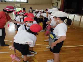 赤い帽子と白い帽子で分かれて並んでいる生徒が教師から指導を受けている写真