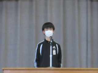 壇上でジャージ姿にマスクをつけている6年生がスピーチをしている写真