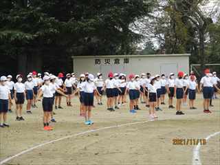 防災倉庫付近の校庭に広がって深呼吸をして体調を整えている子どもたちの写真