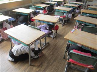 避難訓練で教室の机の下に身を隠している生徒たちの写真