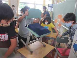 教室内の机や椅子を移動させている生徒たちの写真