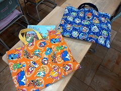 オレンジの柄と青い柄の描かれた手提げ袋2つの写真