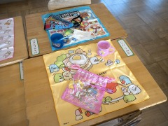 机の上に置かれた、キャラクターの描かれた給食袋とナフキンとマスクと歯ブラシとプラスチック製コップの写真