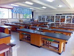 中央に蛇口が設置された黒い天板の細長い机がいくつも並んでいる様子の理科室の写真